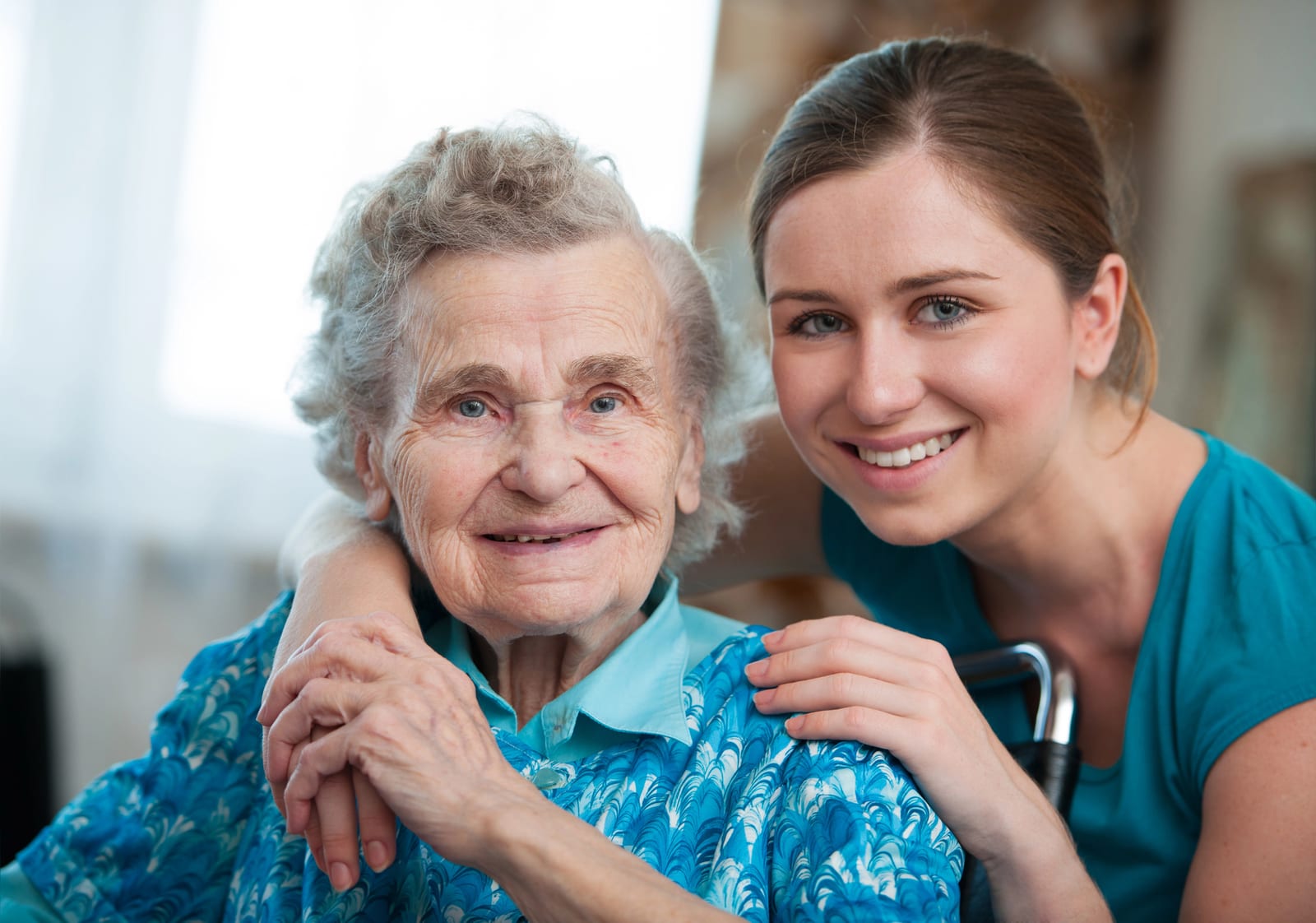 A care advocate with her arm around a smiling older woman